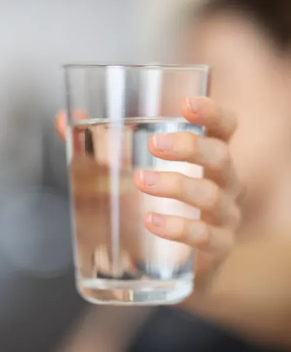 Hand holding a glass of clean, filtered drinking water.
