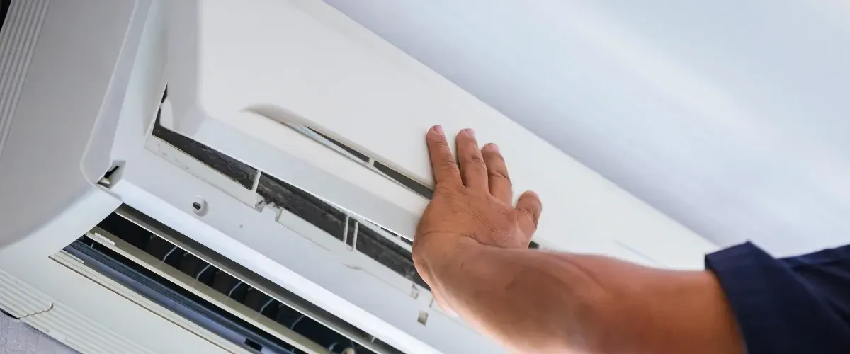 Person cleaning an air conditioner filter by lifting the front panel.