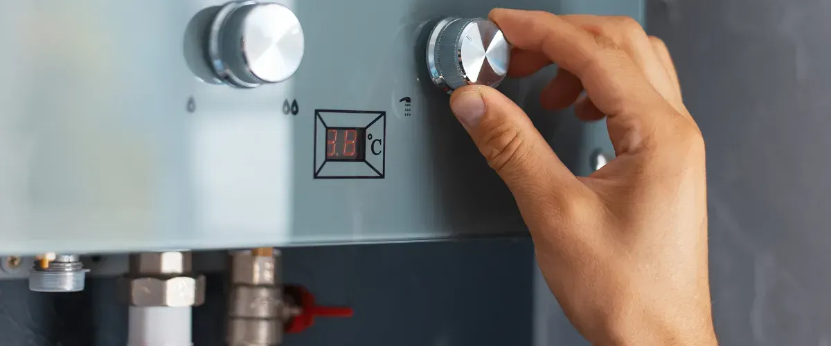 Hand adjusting temperature knob on a home water heater system