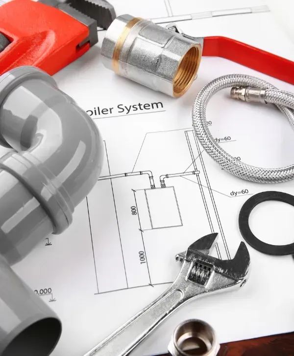 Assorted plumbing tools and fittings laid out on top of a plumbing system blueprint