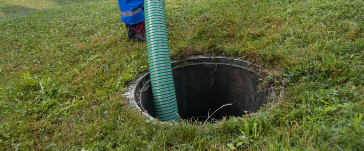 Green hose inserted into septic tank for pumping service