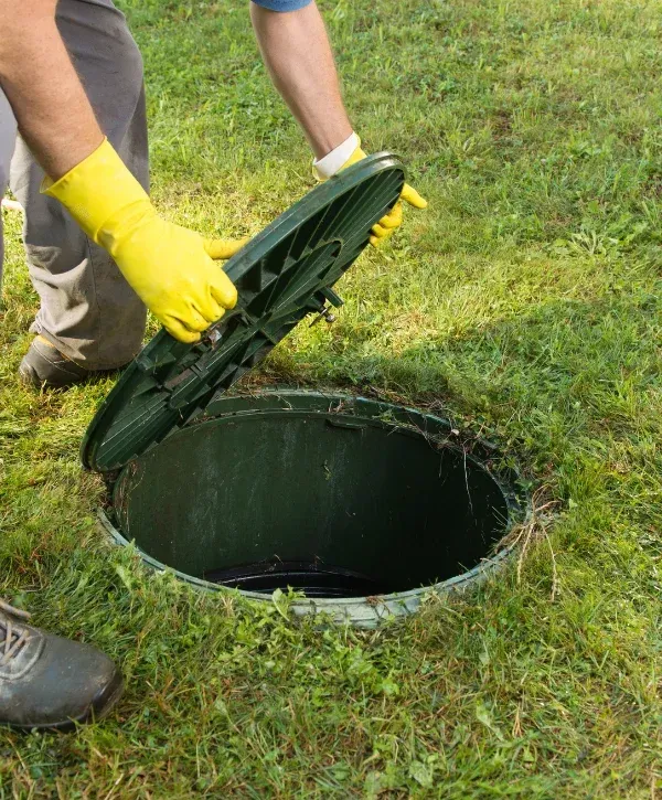 Technician opening septic tank lid with protective gloves