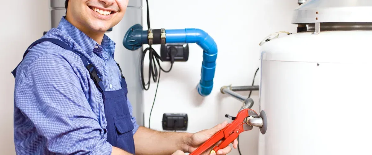 Plumber tightening connection on a residential water heater tank.