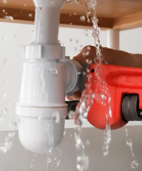 Repairing a leaking sink drain pipe using a pipe wrench.