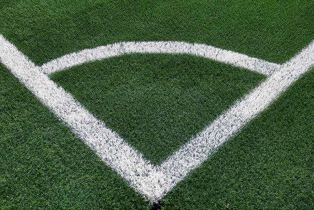 Green astroturf showing the corner of a soccer field, with crisp white lines spray-painted on the turf.