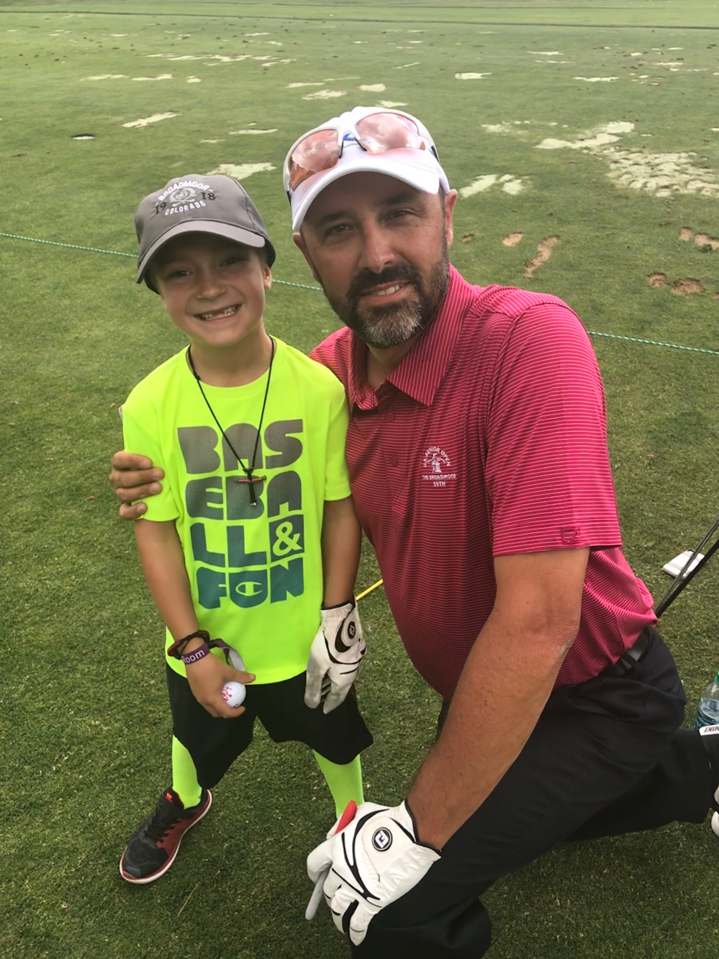 Portrait of Scott Pieri, middle-aged male golf coach, smiling confidently, standing on a golf course with a subtle blurred background, wearing a branded polo shirt and cap, natural daylight, 1:1 aspect ratio.