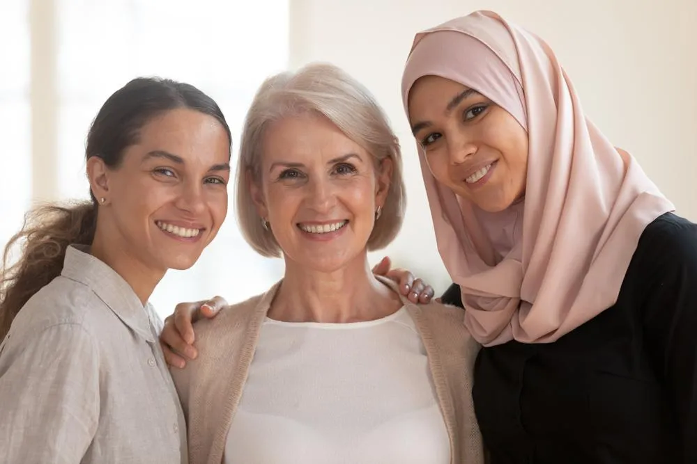 Three multi-generational women embracing and looking at the camera.