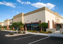 A row of green and blue trash cans next to a building