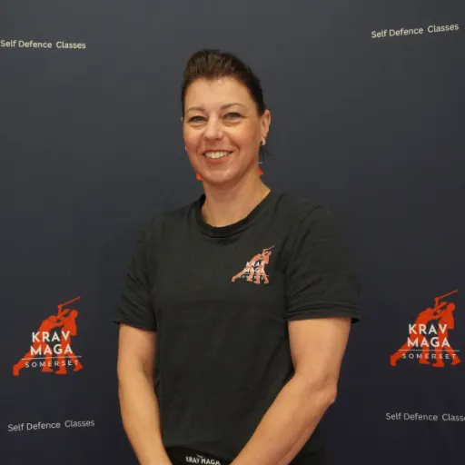 Young female coach, late 20s, demonstrating a kick, energetic, long hair tied back, modern gym setting, 1:1 aspect ratio