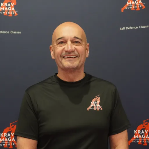 Young female coach, late 20s, demonstrating a kick, energetic, long hair tied back, modern gym setting, 1:1 aspect ratio