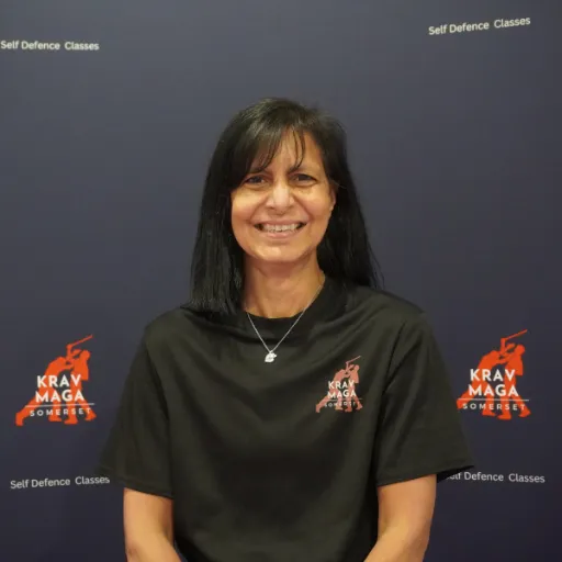 Male instructor, early 40s, leading a group drill, muscular build, friendly expression, diverse students in background, 1:1 aspect ratio