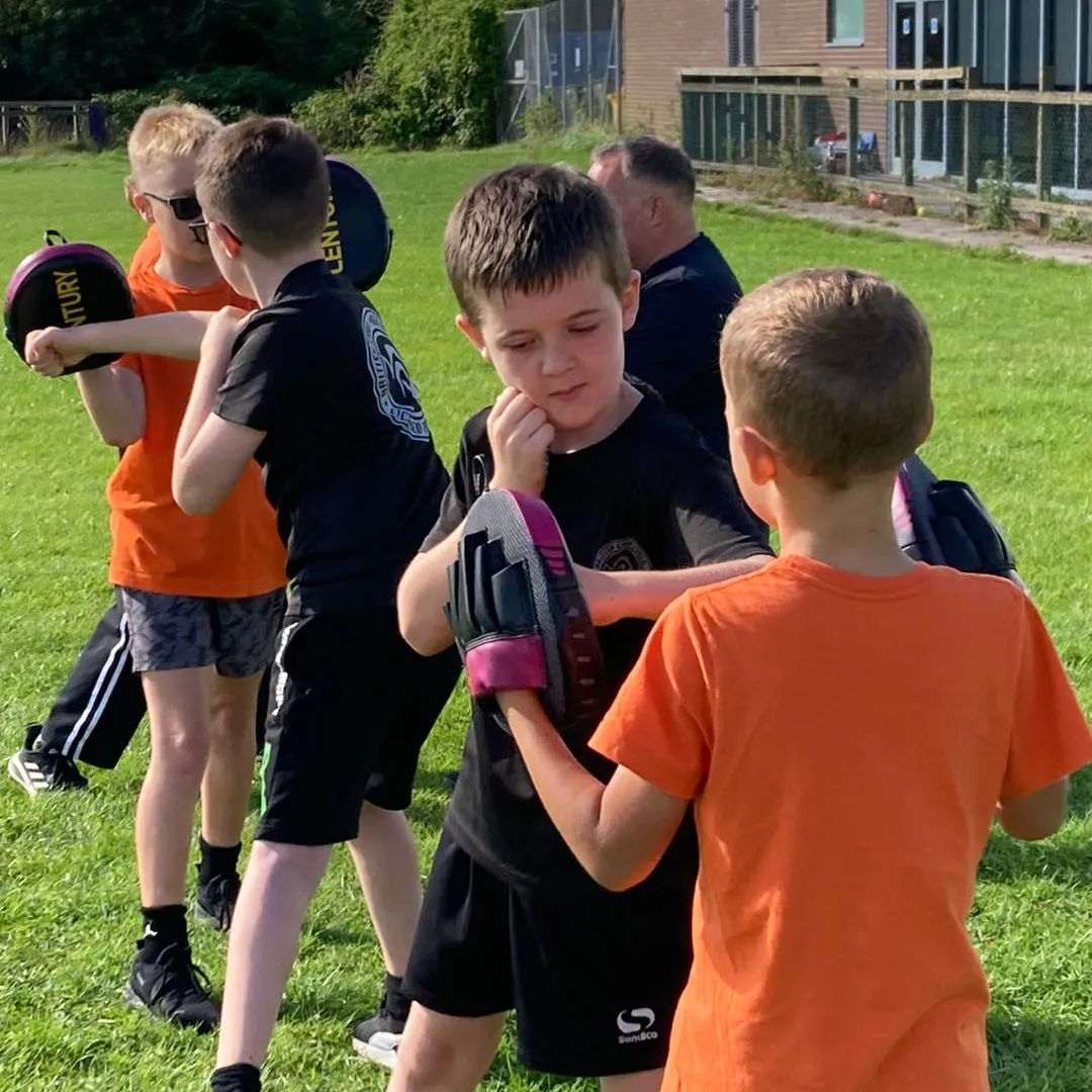 Childrens Martial arts classes Tauntonmartial arts uniforms, all giving a thumbs-up in a bright, welcoming gym with motivational posters on the wall.