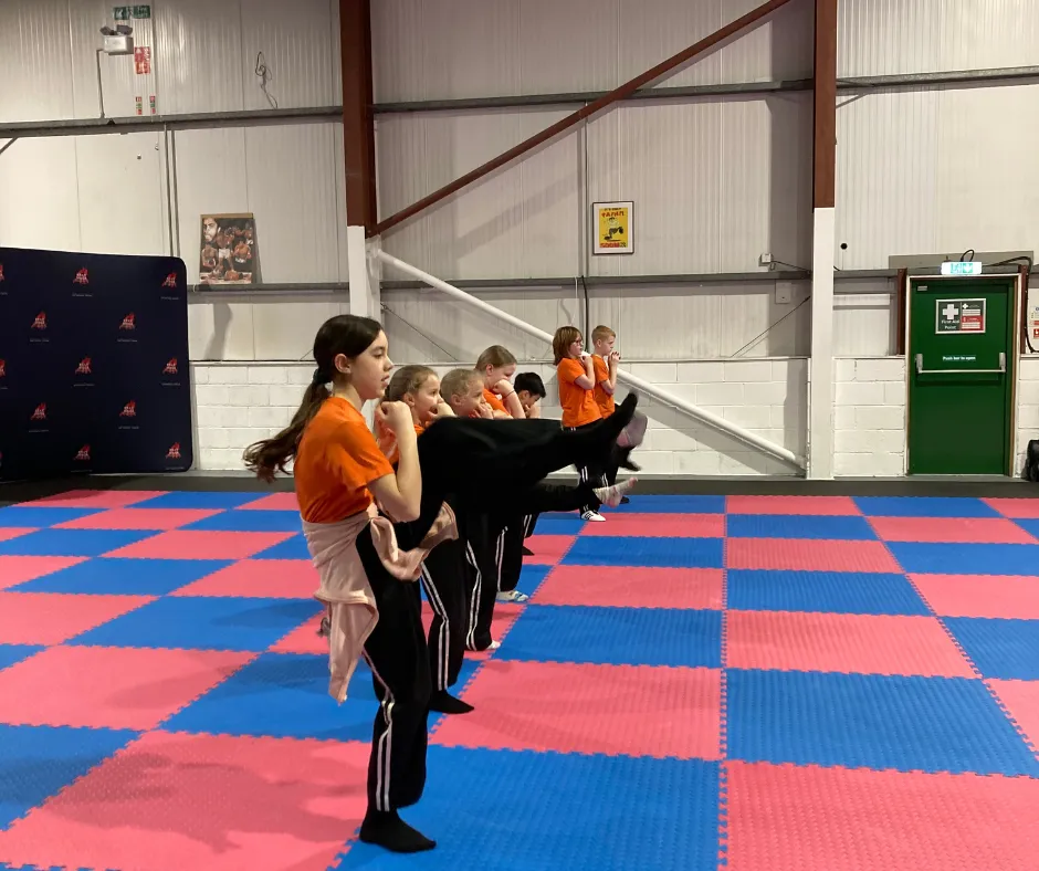 Childrens Martial arts classes Bridgwater martial arts uniforms, all giving a thumbs-up in a bright, welcoming gym with motivational posters on the wall.