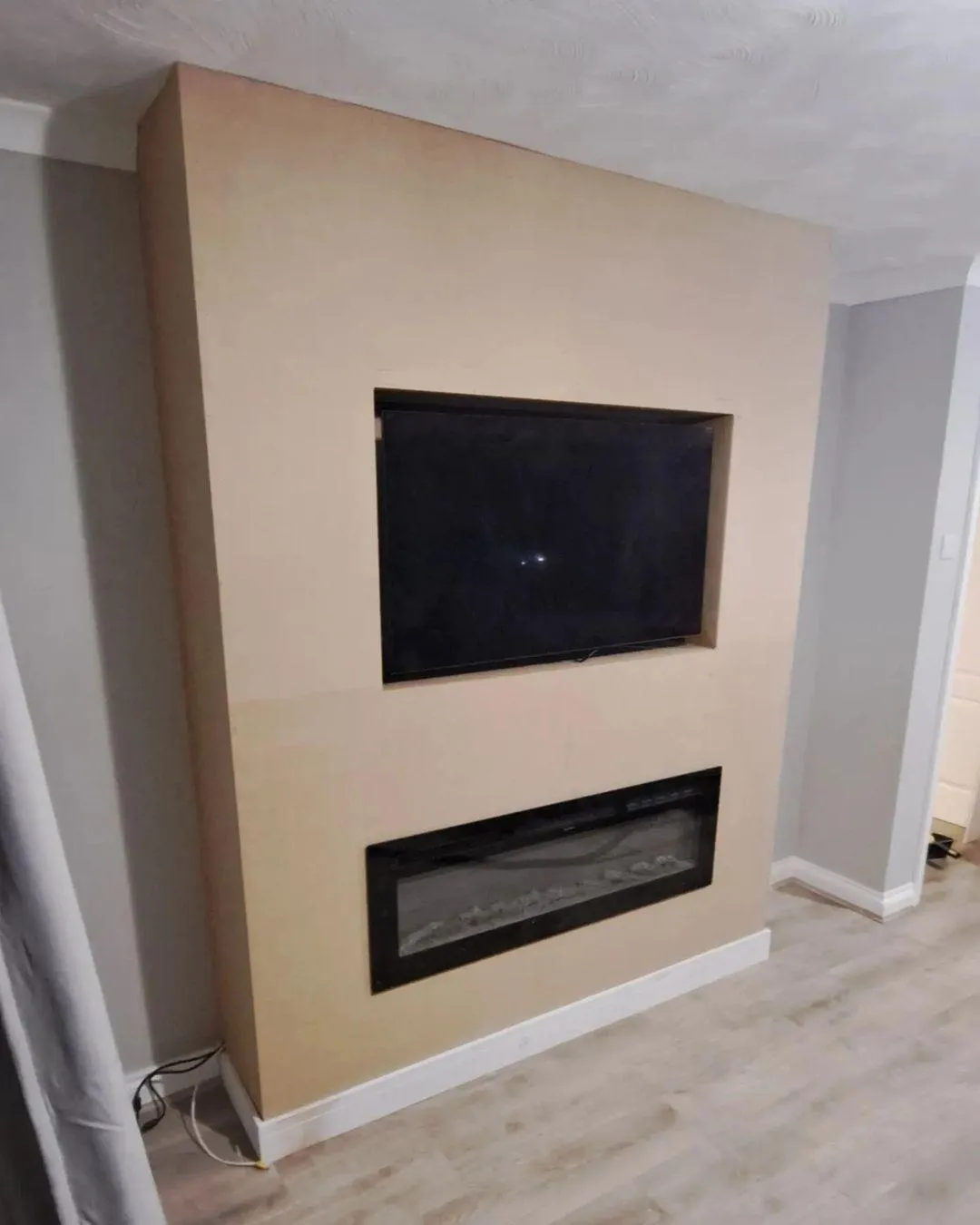 Modern media wall with integrated electric fireplace and recessed space for a flat-screen TV, meticulously constructed by a skilled joiner in the West Midlands, UK, to create a seamless and stylish living room feature, reflecting contemporary design and efficient use of space.