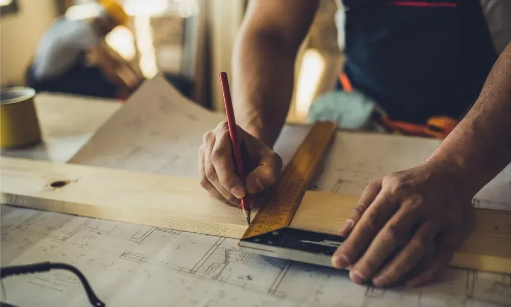 a person using a ruler to draw a piece of wood