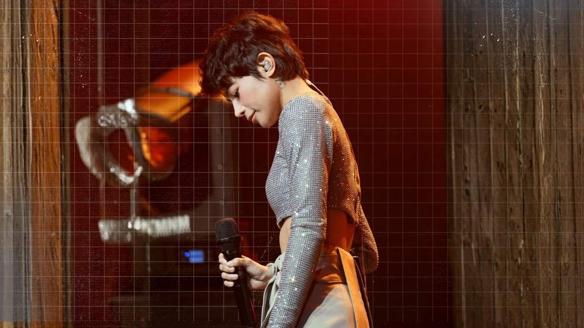 Gigi De Lana performing on stage during a live concert.