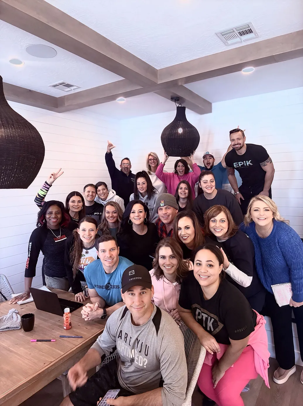 A lively team of Momentum Pro members gathered indoors for a collaborative work session, smiling and celebrating community, mentorship, and business growth.
