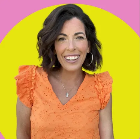 Woman in bright orange top smiling in front of a bold yellow and pink circular background
