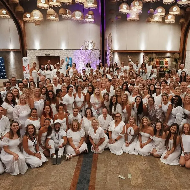 Large group of women dressed in white, gathered for a Momentum Pro event inside a grand venue, symbolizing unity, celebration, and empowerment.