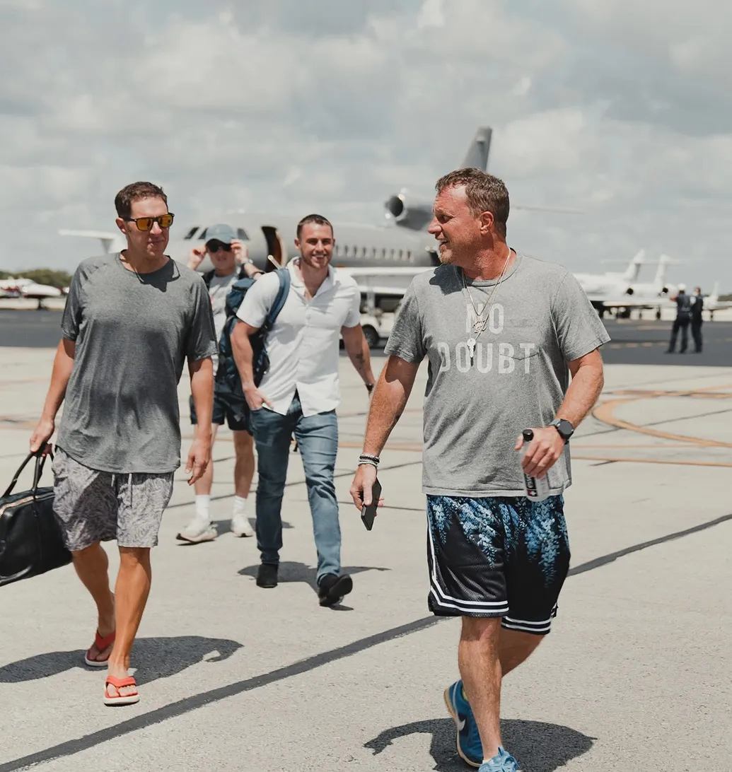 A group of casually dressed men walking confidently on an airport tarmac after deplaning a private jet, symbolizing freedom, success, and lifestyle through entrepreneurship.