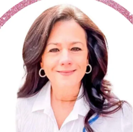 Woman with long dark hair wearing a white shirt, smiling in front of a white and pink sparkly background