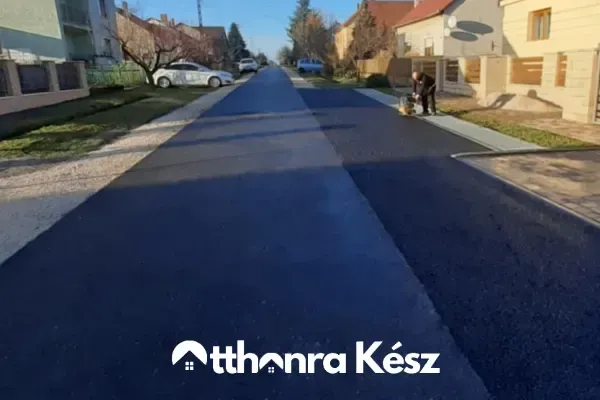 Nagyobb útszakasz aszfaltozása és gépi tömörítése útépítési munkálatok során.