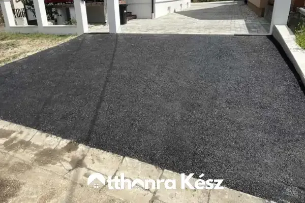 Térkővel burkolt udvar és frissen aszfaltozott kocsibeálló precíz csatlakozása.
