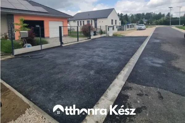 Precíz szegélyezéssel kialakított aszfaltozott kocsibeálló egy modern családi ház bejáratánál.
