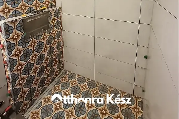 Folyamatban lévő fürdőszoba burkolás mintás padlólappal, rejtett WC tartállyal és lapszintező rendszerrel.