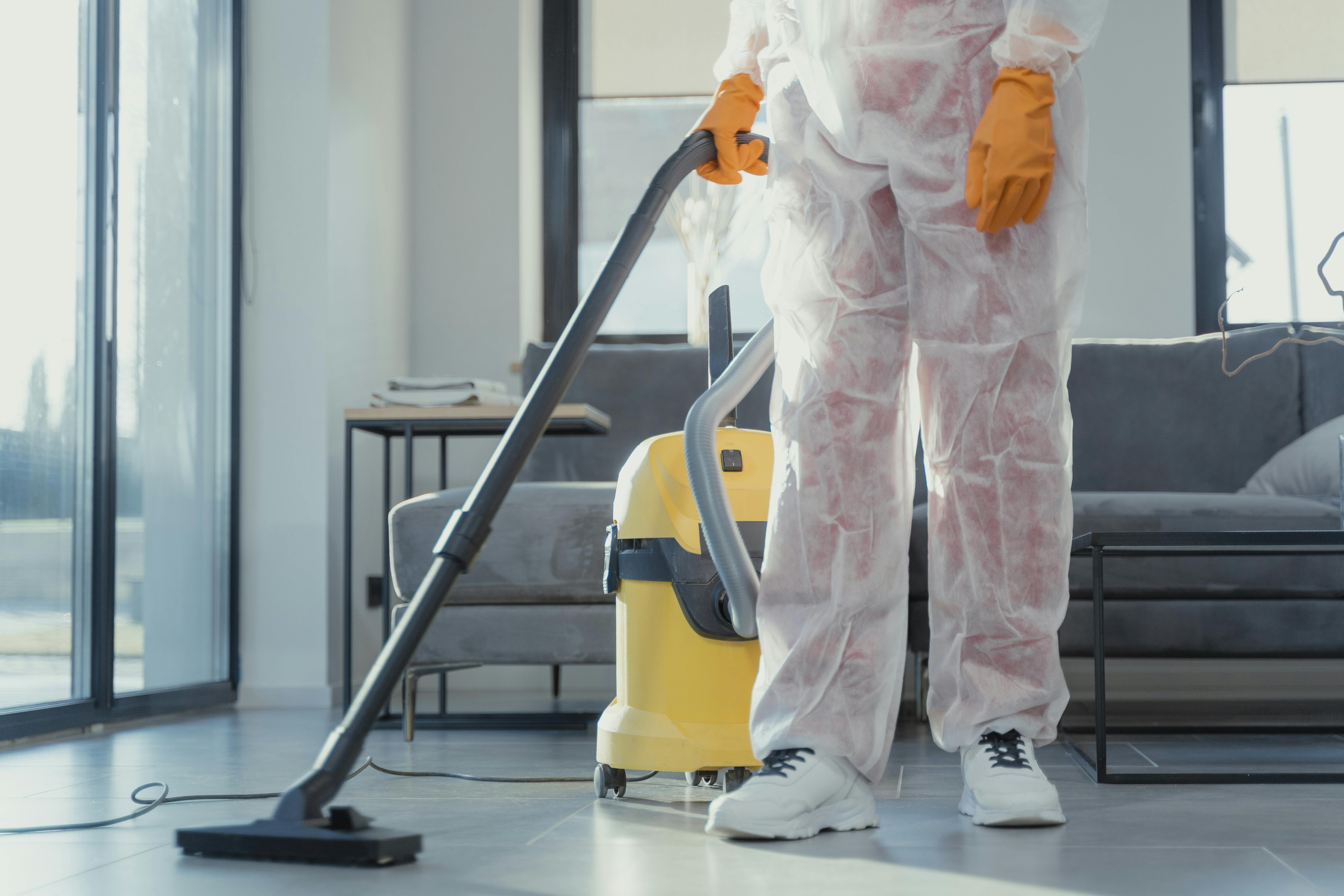 Professionnel du nettoyage utilisant un aspirateur pour assurer l'entretien et la propreté des locaux.