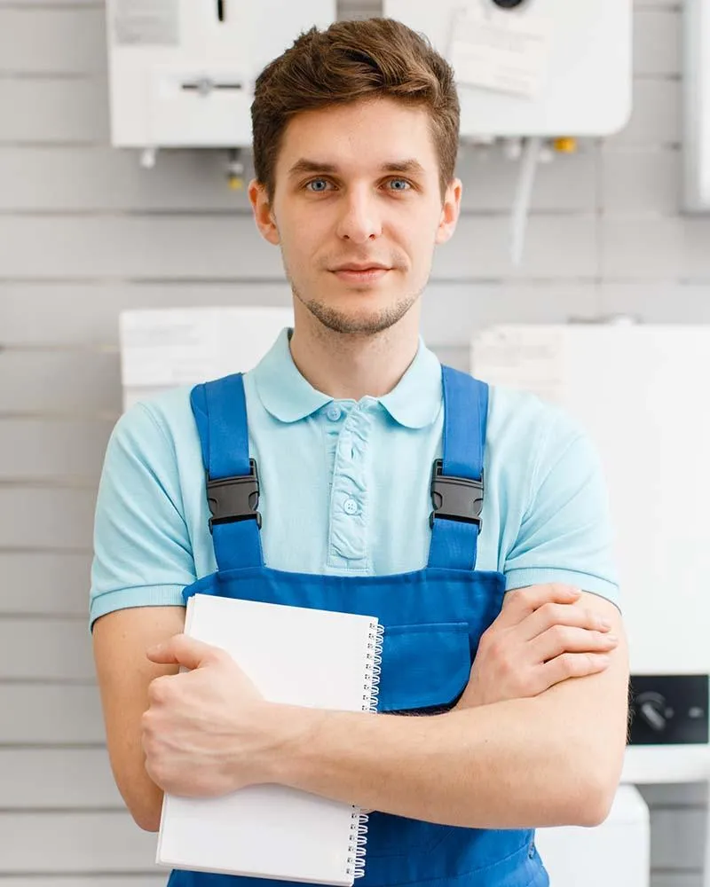 Plumber in blue overalls holding a notepad, standing in a plumbing service environment, representing Fern Plumbing's team of licensed professionals in Miami.