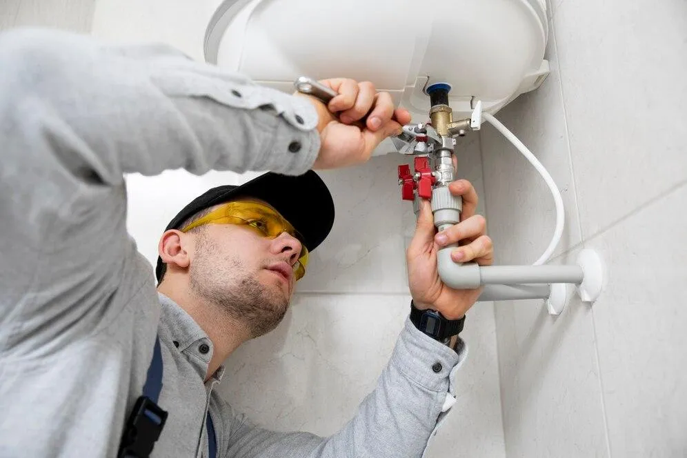Plumber repairing plumbing system with tools, focused on valve adjustment, emphasizing sewer line repair and maintenance services.