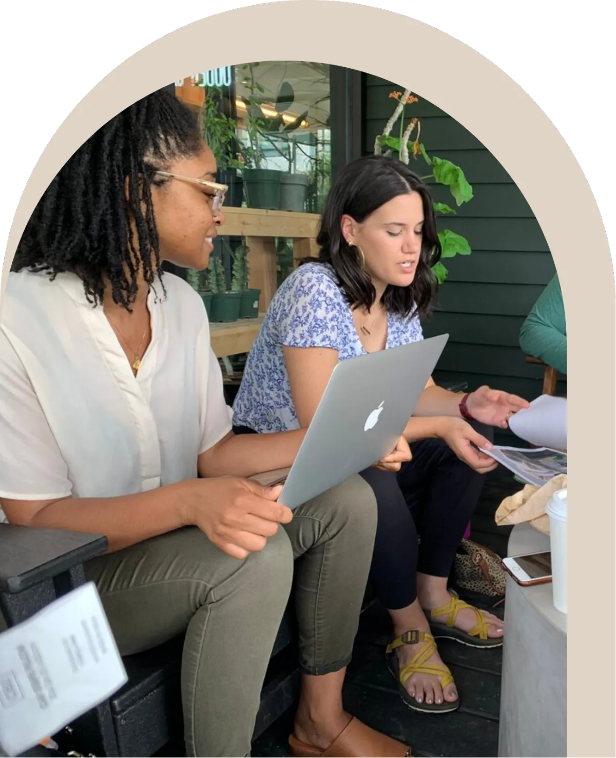 Two women sitting together with a laptop and printed materials