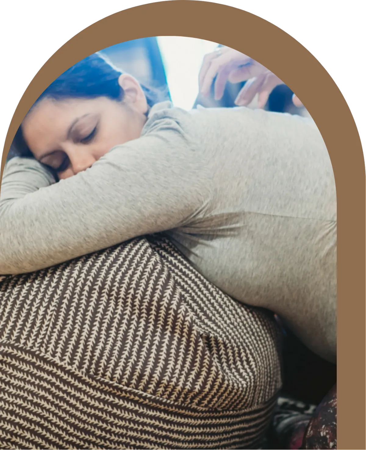 Laboring woman leaning forward onto a birth ball while receiving gentle support