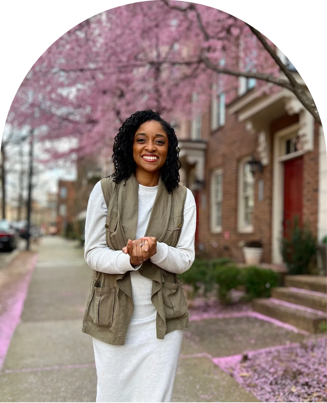Smiling woman standing on a sidewalk lined with pink blossoms