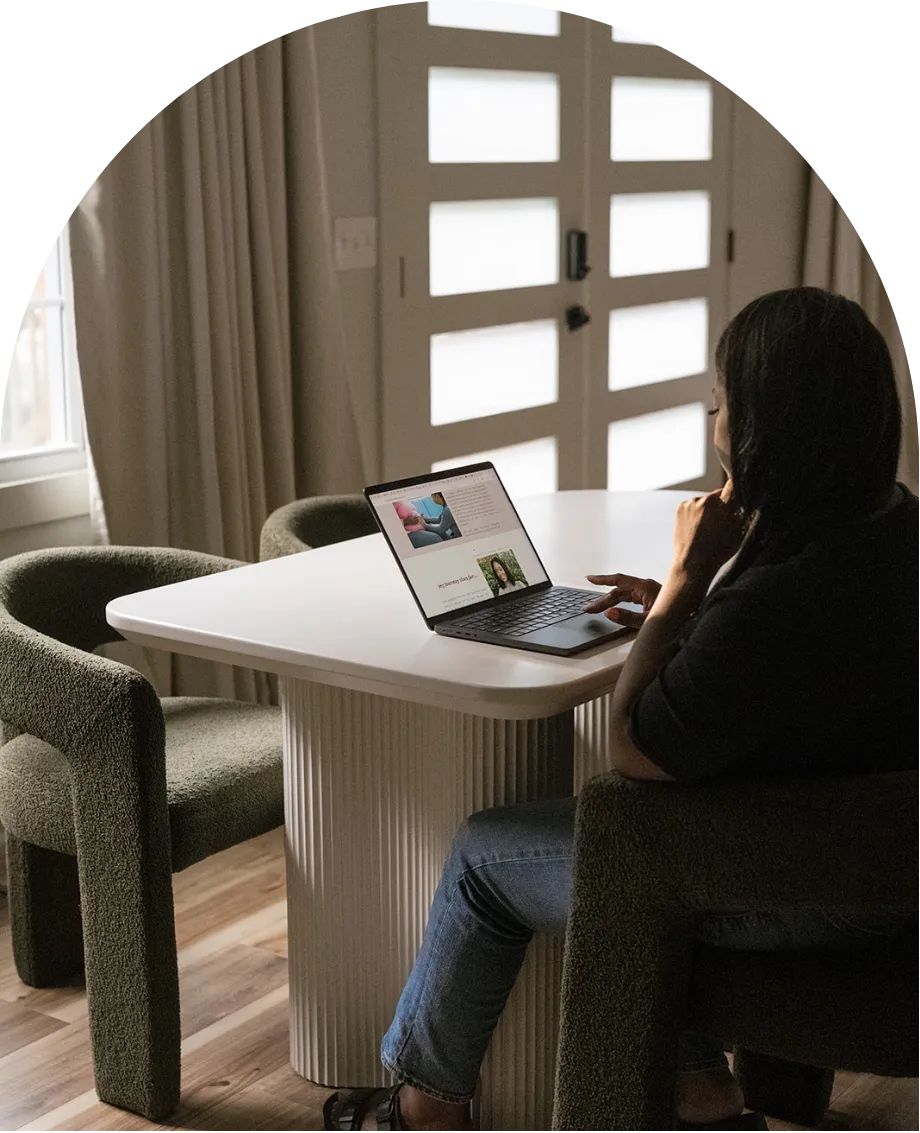 Woman sitting at a table engaging with online birth preparation content on a laptop