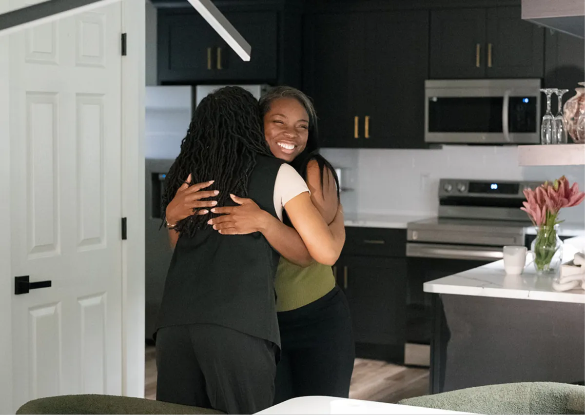 Two women embracing in a warm kitchen setting