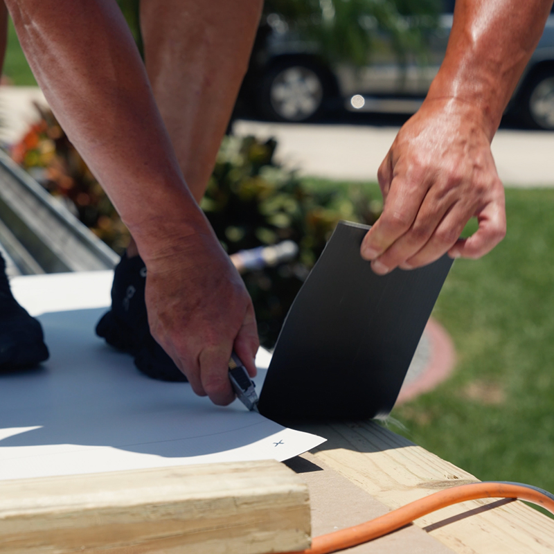 Technician sealing roof edges and penetrations on manufactured home roofing project