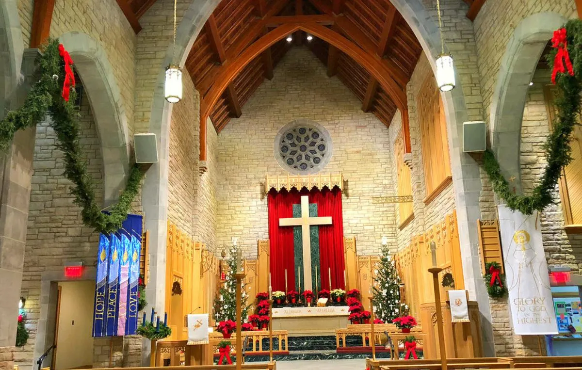 Sanctuary Christmas floral design showcases lush arrangements of red roses, greenery, and candles for holiday joy.