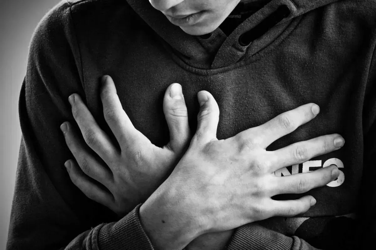 Person holding their chest with crossed arms in a close-up shot.