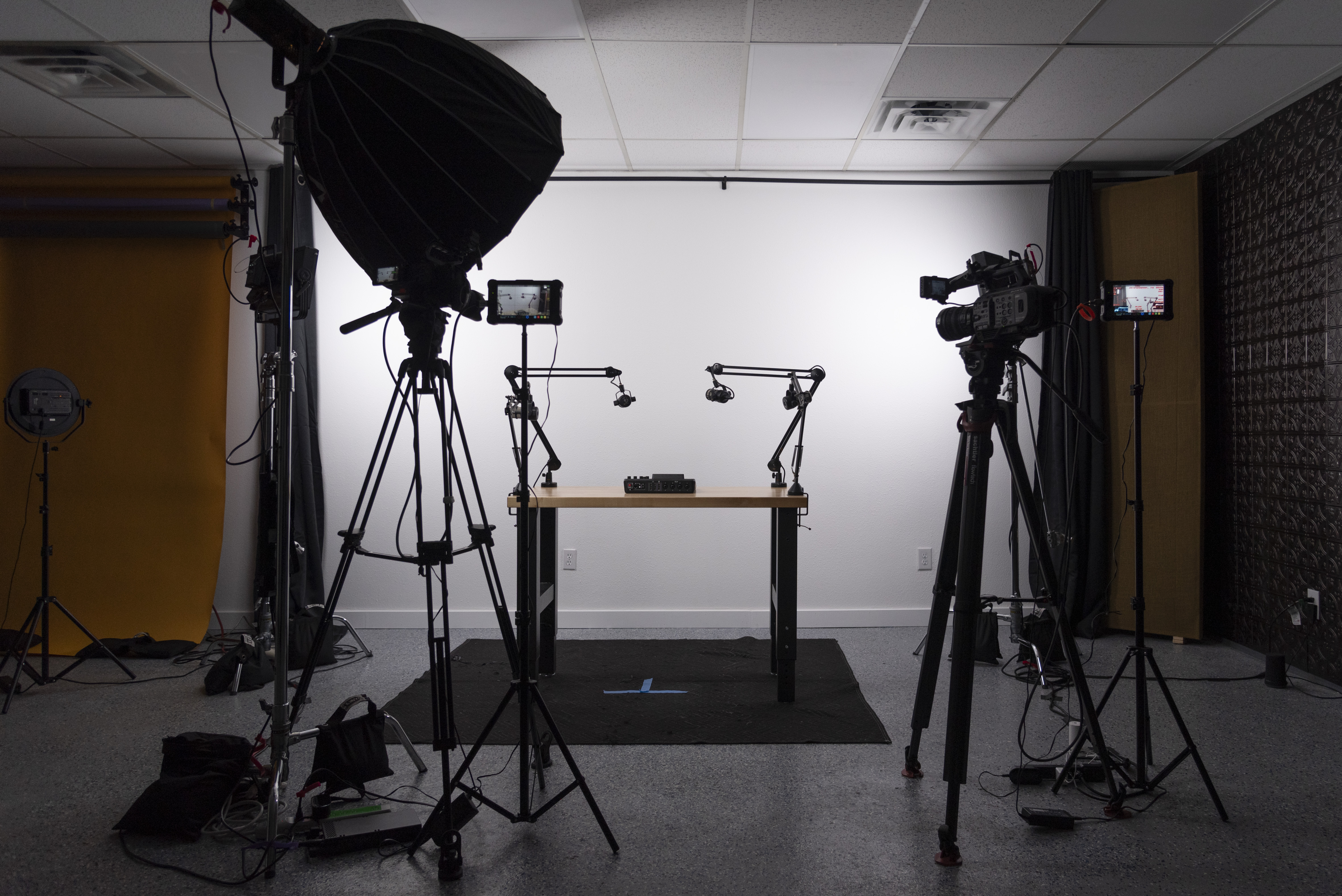 Podcast recording set up in front of a white wall with lights, cameras and audio recording equipment.