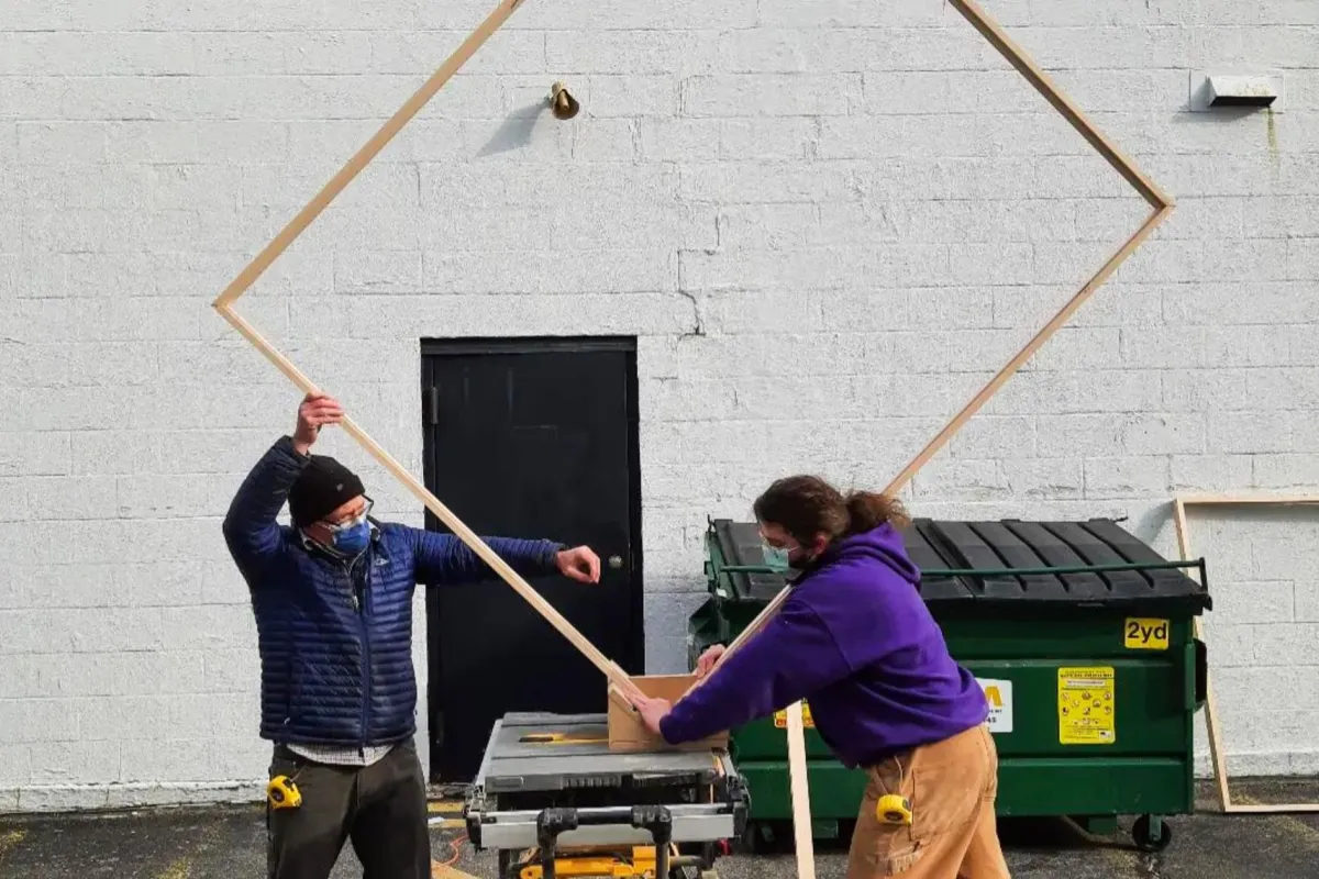 Framers handling a large custom wood frame for oversized artwork