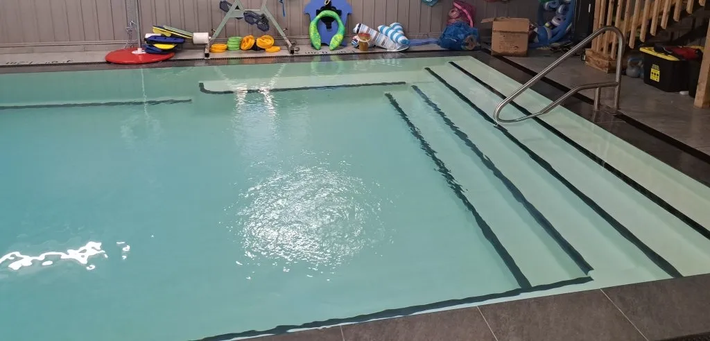 Wide, calm heated swimming pool with gentle entry steps and supportive aquatic equipment