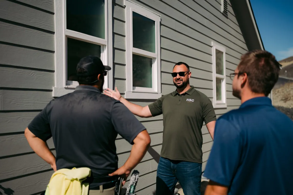 Adam Diaz talking with two home-service owners outside a house
