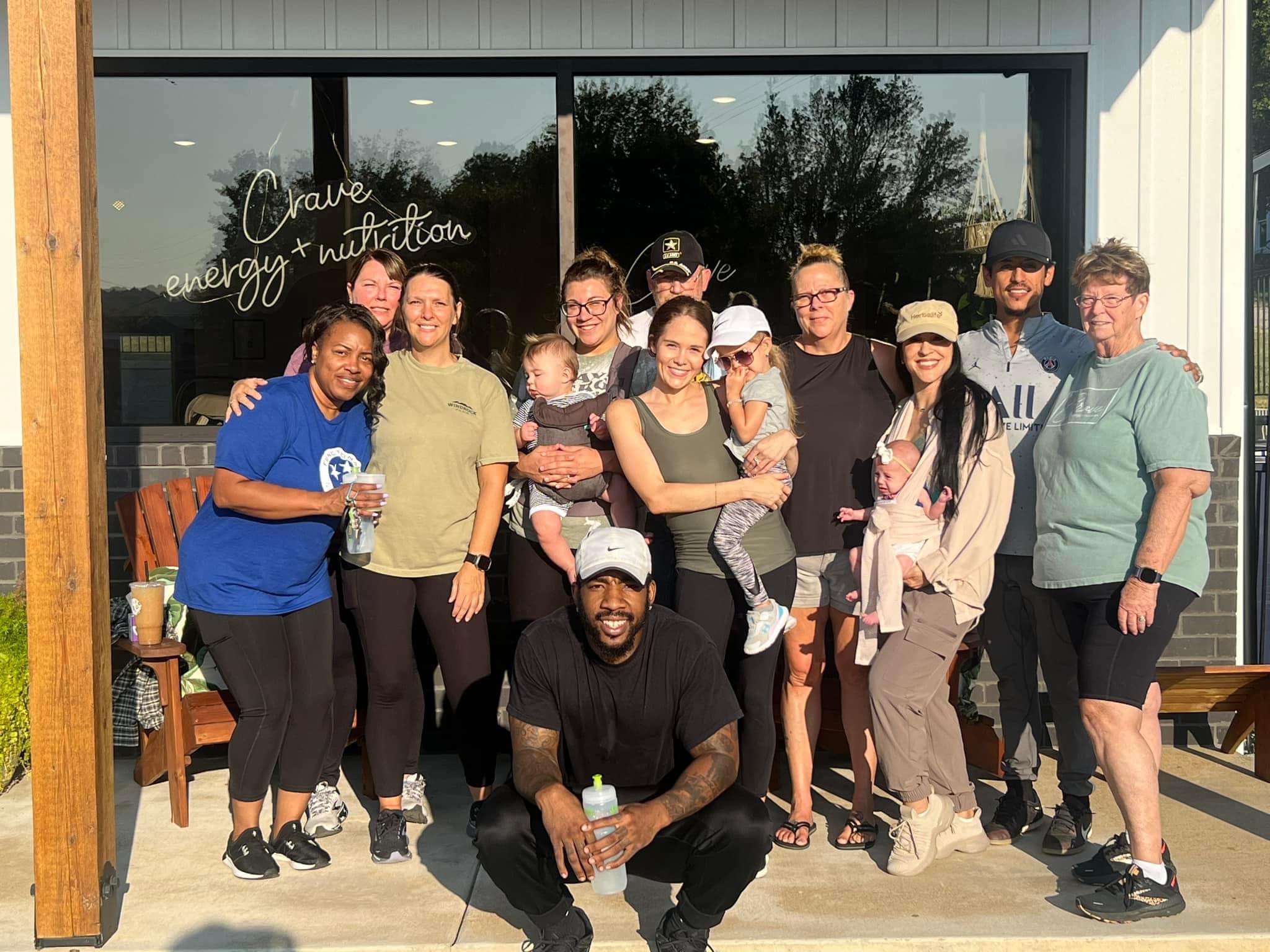Young parent working on a laptop at a kitchen table while a child draws nearby, showing work-life balance