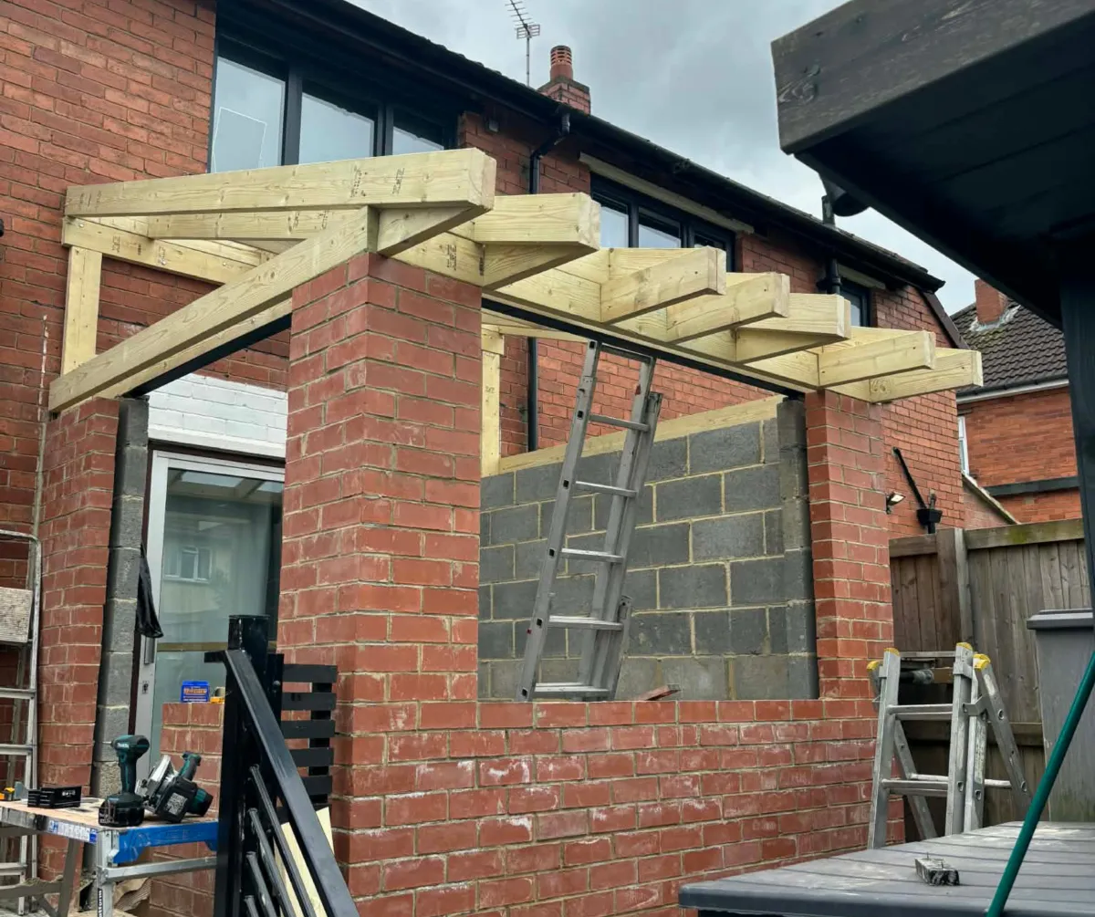 Brick home extension under construction with timber roof structure in Lancashire
