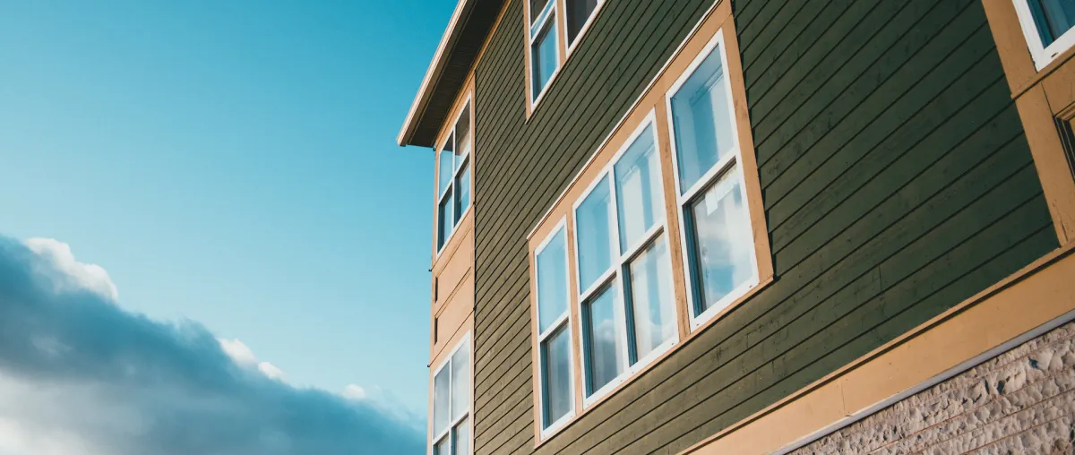 Green and yellow siding on a modern home with large windows, showcasing durable exterior materials suitable for siding installation and repair services offered by Right Roofing.