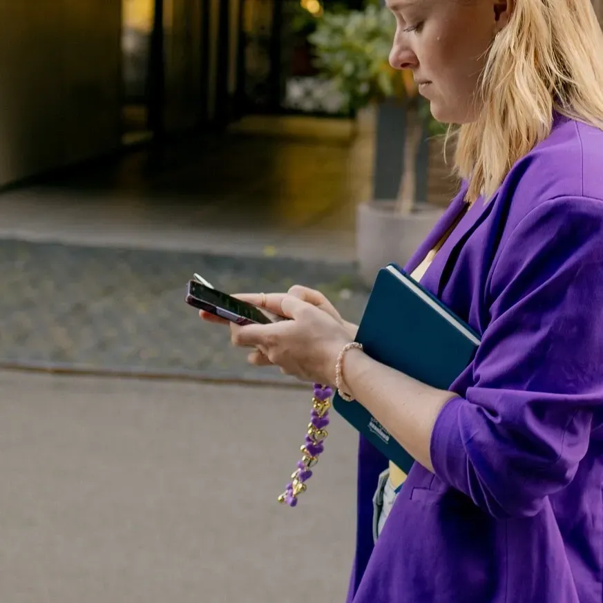 Ondernemer gebruikt haar telefoon en notitieboek buiten een zakelijke bijeenkomst
