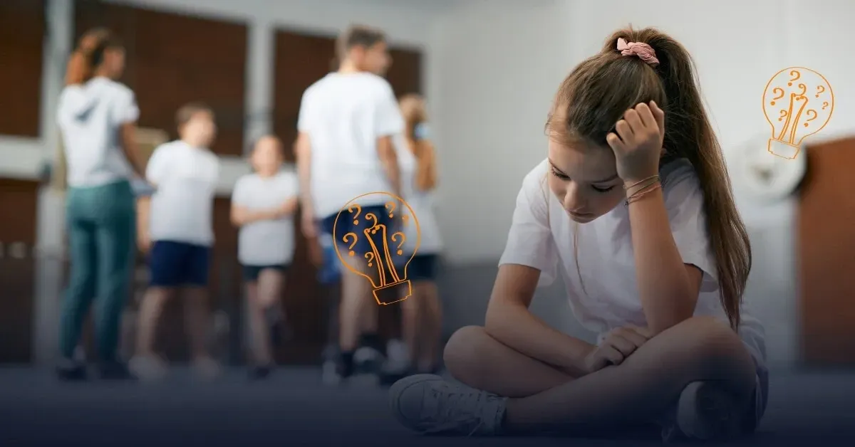 Primary-age pupil sitting on the floor in a school gym, looking reflective while other children talk in the background, with illustrated lightbulb icons – cover image for a Behaviour Smart blog about behaviour support, school interventions and understanding pupils’ experiences.