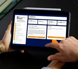 Person using a tablet showing the Behaviour Smart dashboard with behaviour incidents, alerts and analytics for UK schools.